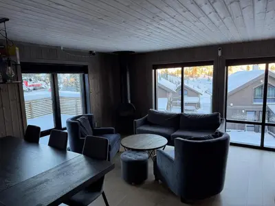 a living room with couches and a table and windows at Kvitfjell Year-round destination-Ski in ski out - World Cup side in Strande