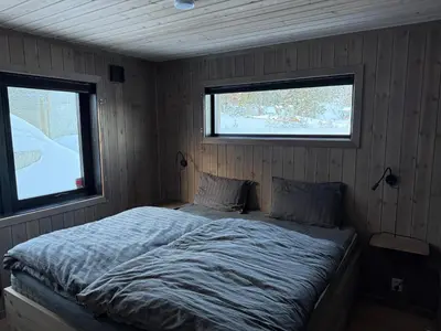 a bed in a room with two windows at Kvitfjell Year-round destination-Ski in ski out - World Cup side in Strande