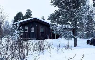 a wooden cabin in the snow with a car parked in front at Amazing Home In Rauland in Rauland