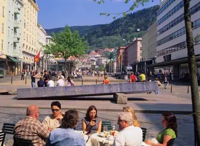 a group of people sitting at tables on a city street at City center retreat with king bed in Bergen