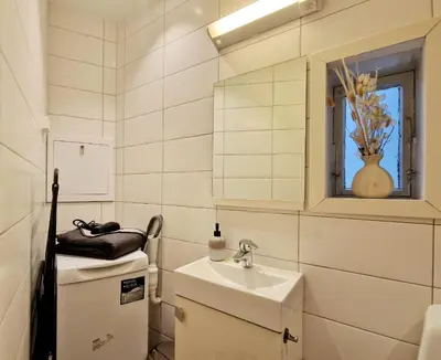 a small white bathroom with a sink and a mirror at City center retreat with king bed in Bergen