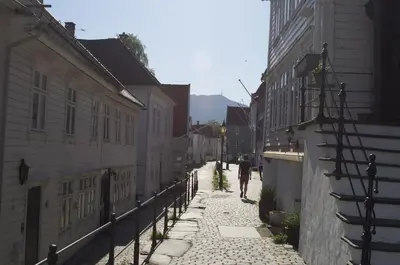 a person walking down a cobblestone street between buildings at Historic Bergen house, right in the middle of everything! in Bergen