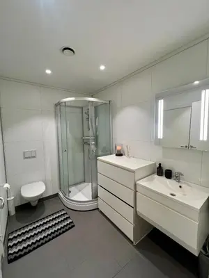 a white bathroom with a shower and two sinks at Moderne hjem med høy standard og privat takterasse in Trondheim