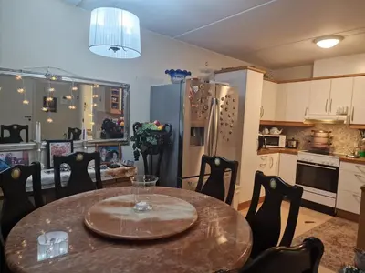 a kitchen with a table with chairs and a refrigerator at Flatåsensenteret in Kystad