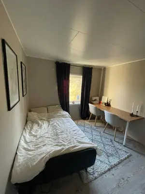 a bedroom with a bed and a table and a desk at Cozy and spacious apartment in Trondheim