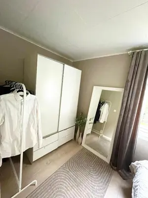 a bedroom with white cabinets and a mirror at Cozy and spacious apartment in Trondheim
