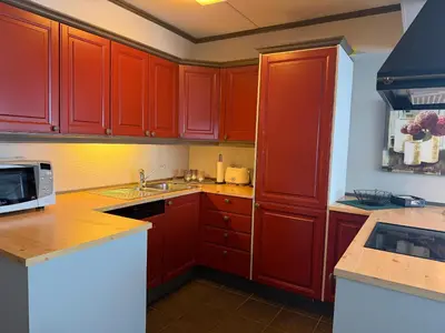 a kitchen with red cabinets and a microwave at Spacious Retreat With Sauna And Parking in Beitostøl