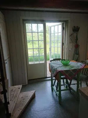 a dining room with a table and a glass door at Cozy Cabin Retreat in Scenic Valley, E6 south of Trondheim in Storen