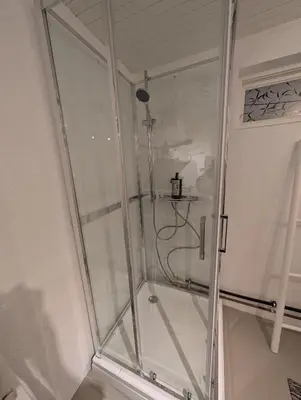 a shower with a glass door in a bathroom at Koselig kjellerleilighet, gratis parkering! in Trondheim