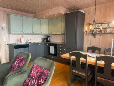 a kitchen with green cabinets and a table and chairs at Spacious Apartment For Up To 5 Guests in Beitostøl