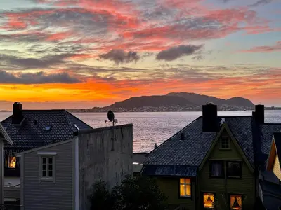 a sunset over the water and houses in a city at Apartment with a beautiful view in the center of Ålesund in Ålesund