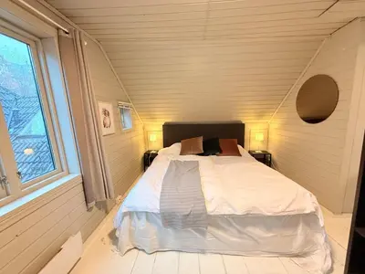 a bedroom with a bed in a room with a window at Historic Charm in Bergens Heart in Bergen