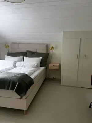 a bedroom with a white bed with a black blanket at Grandma`s house in Flåm