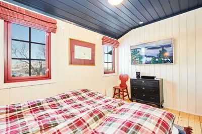 a bedroom with a bed and a dresser and windows at Newly renovated, centrally located family cabin with mountain view in Beitostøl