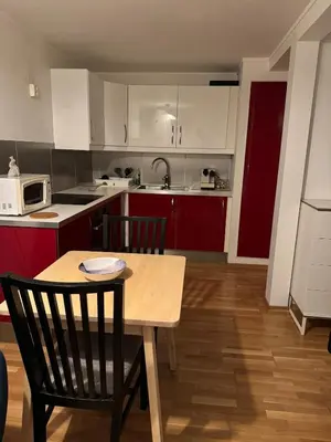 a kitchen with red and white cabinets and a table and chairs at Nice apartment in quiet neighborhood in Trondheim