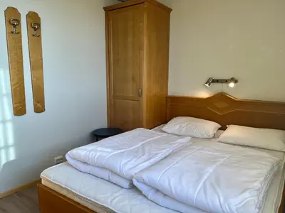 a bed with white sheets and a wooden headboard at Leilighet midt i sentrum in Beitostøl