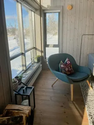 a living room with a blue chair and windows at Enjoy The Calm Setting Of This Cozy Family Cabin in Etnedal