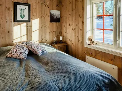 a bedroom with a bed with pillows and a window at Fantastic View Cabin In Peaceful Blefjel in Lampeland