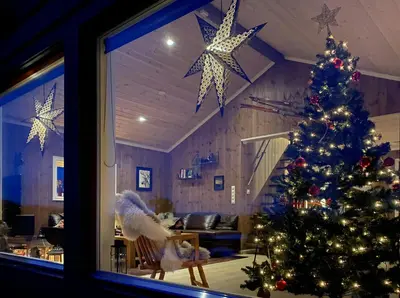 a christmas tree in a living room with a window at Fantastic View Cabin In Peaceful Blefjel in Lampeland