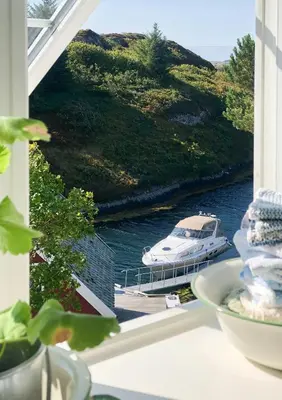 a boat is docked at a dock on a river at Historic Villa By The Sea In Solund in Hardbakke