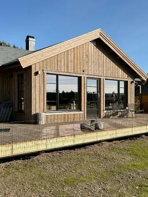 a house with windows and a deck with chairs at Cozy Modern Mountain Cabin At Kvamsfjellet in Kvam
