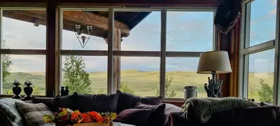 a living room with a large window with a couch at Cozy Cabin With A Beautiful View in Øygardsgrend