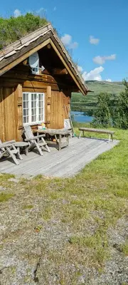 a wooden cabin with a picnic table and a bench at Cozy Cabin With A Beautiful View in Øygardsgrend