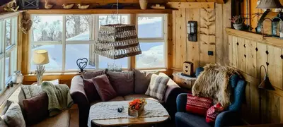 a living room with a couch and a table at Cozy Cabin With A Beautiful View in Øygardsgrend