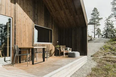 a wooden house with a table and chairs on a deck at Cabin By Selbusjøen With Ski And Trail Access in Selbu