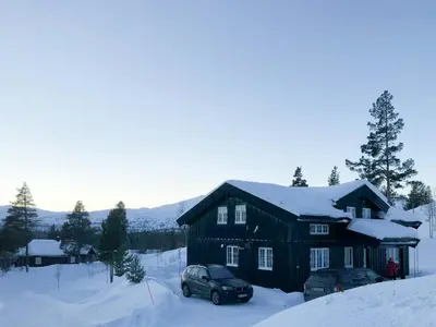 a black house with two cars parked in the snow at Designer Cabin With Panoramic Views In Hovden in Bykle
