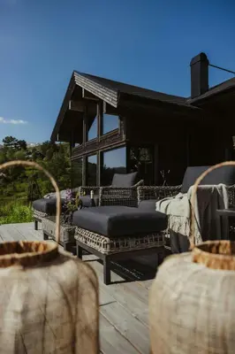 a patio with several wicker furniture on a deck at Architect-Designed Cabin Near Hardangerfjord in Garnes
