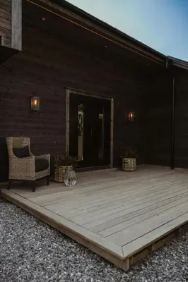 a wooden deck with a chair on a building at Architect-Designed Cabin Near Hardangerfjord in Garnes