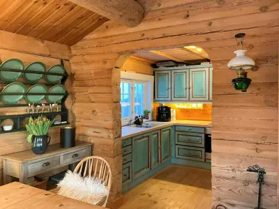a kitchen with green cabinets and a wooden wall at Idyllic Log Cabin At Nordseter in Lillehammer