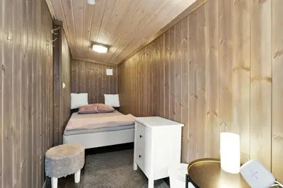 a small bedroom with a bed in a wooden wall at Peaceful Cabin With View And Jacuzzi At Blefjell in Kongsberg