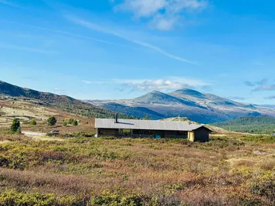a barn in a field with mountains in the background at Architect-Designed Cabin By Rondane in Høvringen