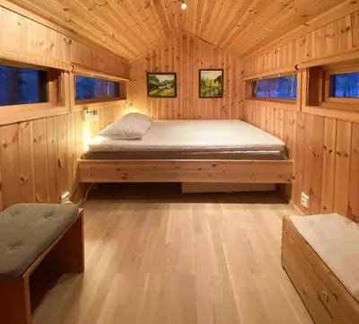 a bed in a cabin with wooden walls and windows at Modern Mountain Cabin Near Hiking Terrain in Geilo