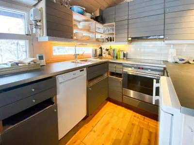 a kitchen with stainless steel appliances and a wooden floor at Modern Mountain Cabin Near Hiking Terrain in Geilo