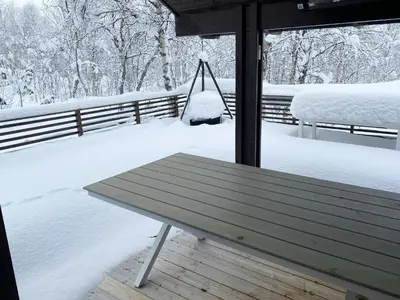 a snow covered porch with a bench and a swing at Modern Mountain Cabin Near Hiking Terrain in Geilo