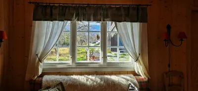 a window with curtains and a bed in a room at Charming Cabin With Views In Valdres in Aurdal