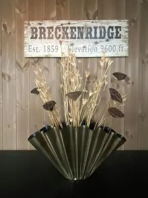a black vase with some dried plants in it at Lovely, New Apartment At Kvitfjell With Ski-In Out in Fåvang