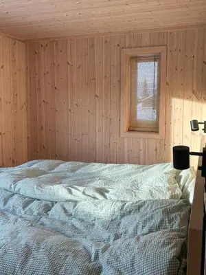 a bed in a wooden room with a window at Fantastic Forest Cabin With Panoramic View in Jaren