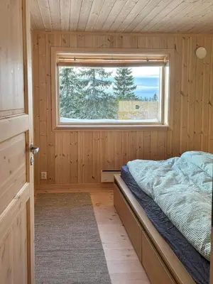 a small bedroom with a bed and a window at Fantastic Forest Cabin With Panoramic View in Jaren