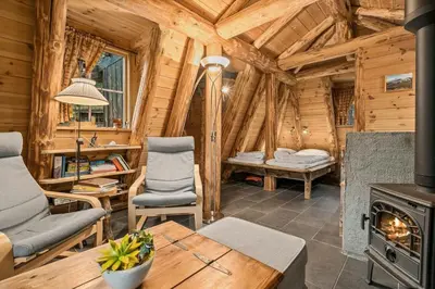 a living room with a stove in a wooden cabin at Unique Hobbit Cabin By Hallingskarvet in Hovet