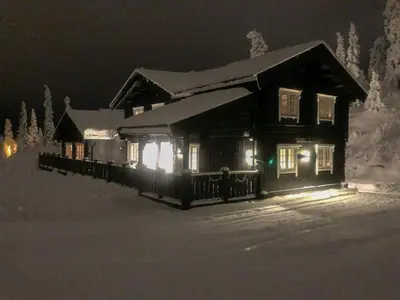 a house with lights in the snow at night at Lovely Luxury In The Spacious Log Cabin In Trysil in Trysil