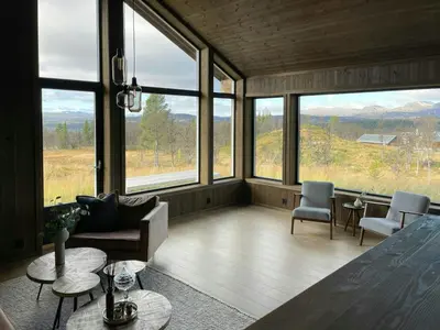 a living room with large windows and a table and chairs at Spacious Mountain Cabin With Fantastic Views in Ål