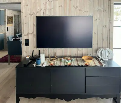 a large black entertainment center with a flat screen tv on a wall at Nature-Close Cabin By The Water in Eggedal