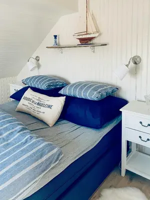 a bed with two blue pillows on top of it at Charming Southern Norway Idyll On Trøndelag Coast in Sula