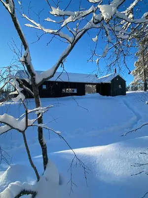 a snow covered field with a barn in the background at Mountain Cabin With Sauna At Blefjell in Lampeland