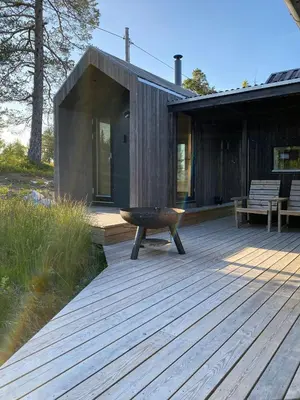 a wooden deck with a fire pit on a house at Mountain Cabin With Sauna At Blefjell in Lampeland