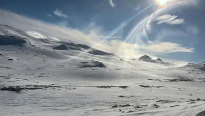 a snow covered mountain with a rainbow in the sky at Rustic Log Cabin At The Foot Of Hardangervidda in Uvdal